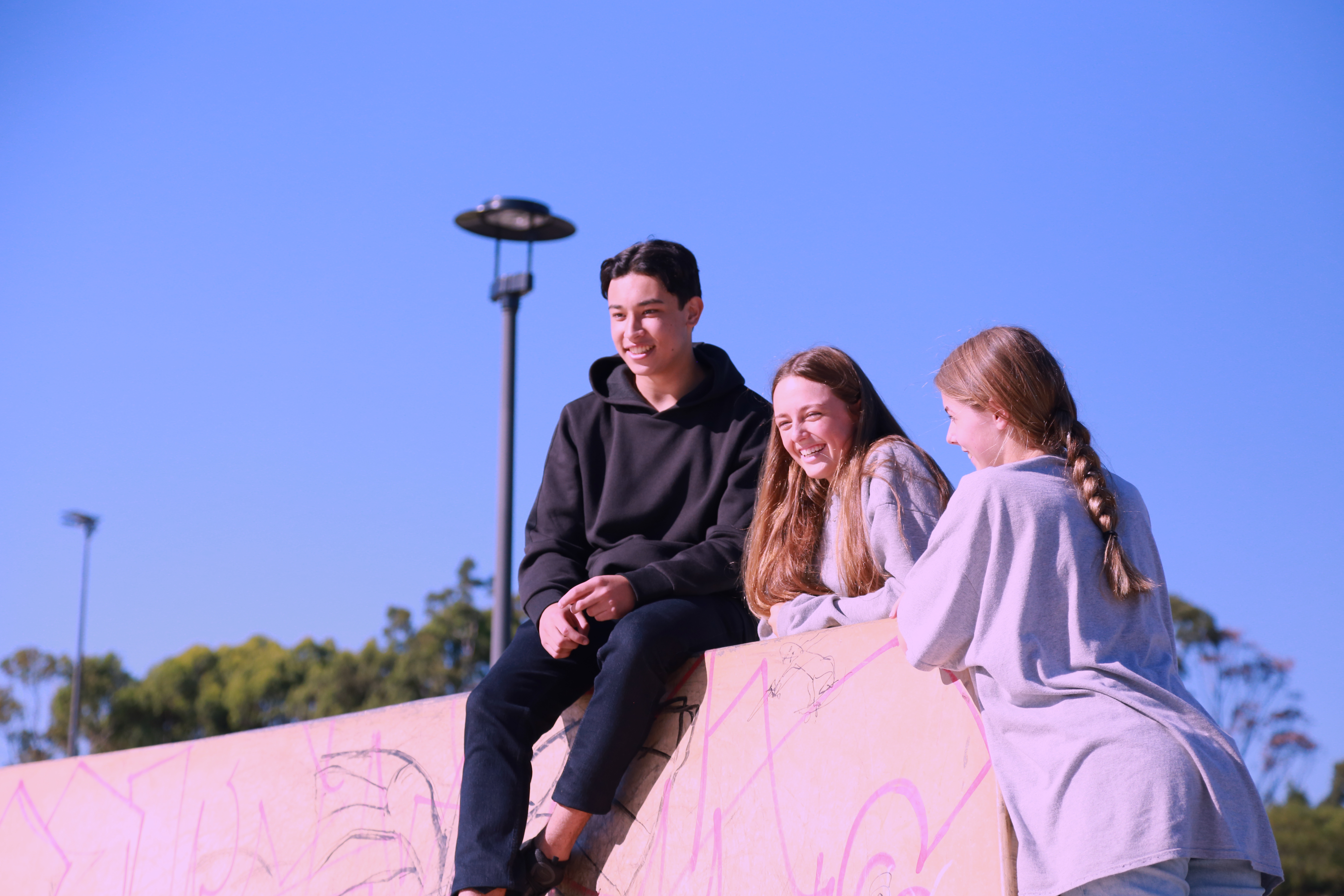 Three teenagers smiling and chatting with each other