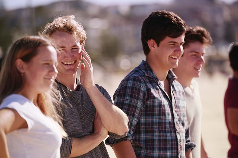 Four teenagers smiling and chatting with each other at the beach